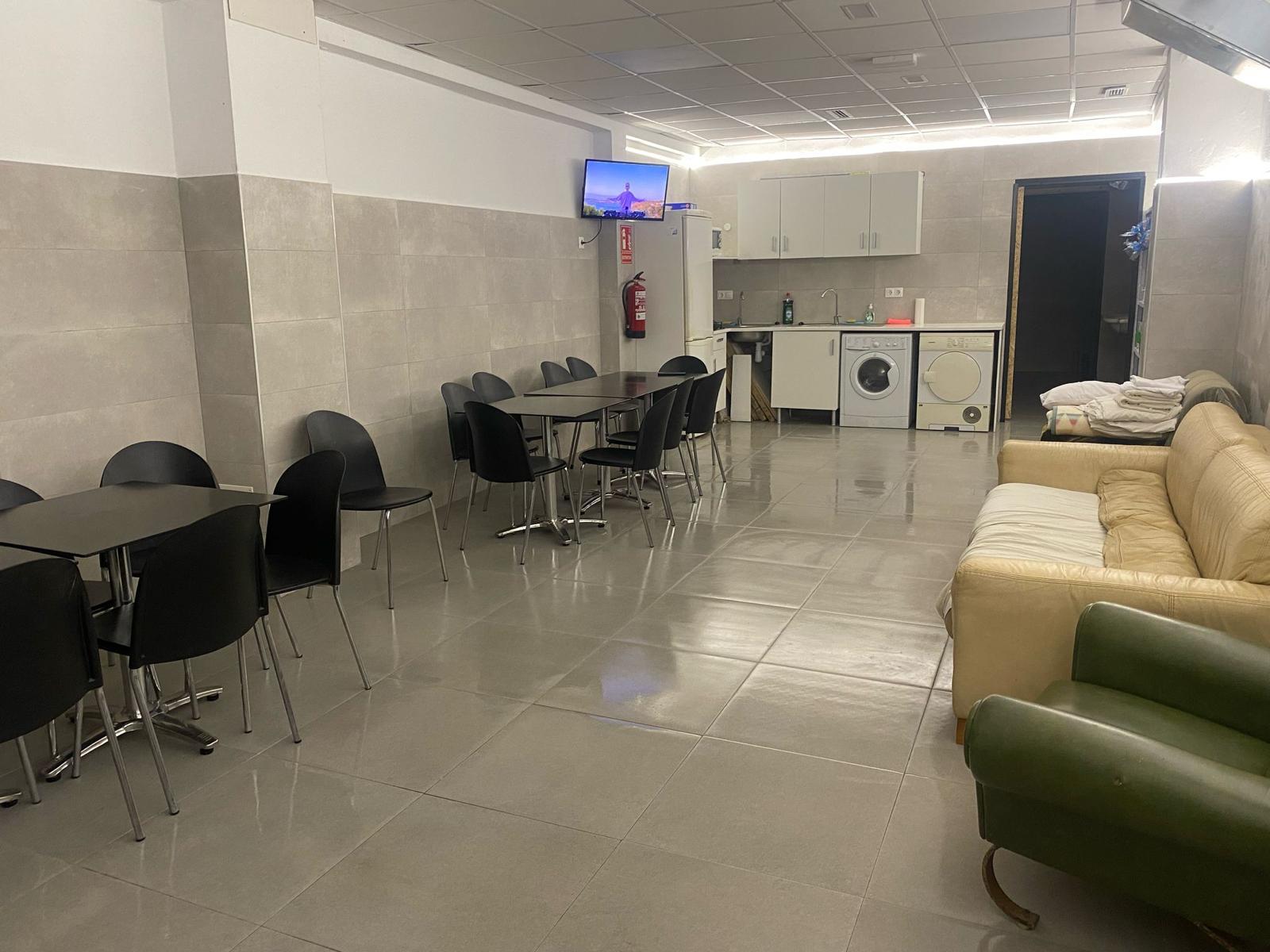 Salón con mesas, sofás y cocina abierta